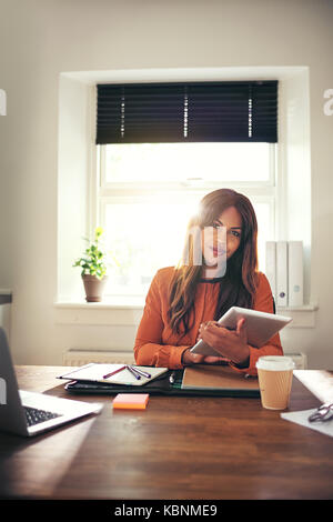 Schwerpunkt junge afrikanische Frauen Unternehmer online arbeiten mit einem digitalen Tablet beim Sitzen an einem Tisch in Ihrem home office Stockfoto