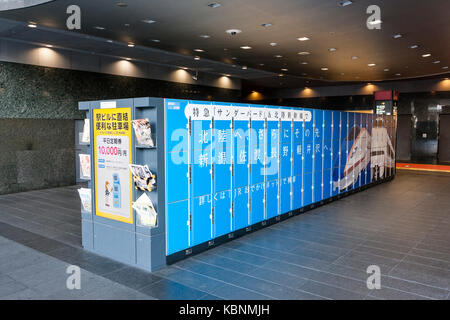 Japan, Kyoto. Bahnhof von Kyoto. Block mit drei Größen der öffentlichen blauen Schließfächer mit Bild der Hokuriku Shinkansen auf. Ende der Block hat Zeitschriftenfach. Stockfoto
