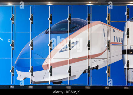 Japan, Kyoto. Bahnhof von Kyoto. Block mit drei Größen der öffentlichen blauen Schließfächer mit Bild der Hokuriku Shinkansen auf. Stockfoto