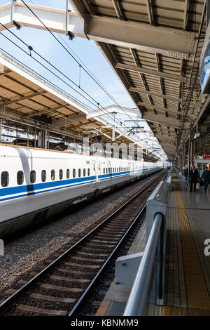 Japan, Kyoto Station. Serie 700 Shinkansen, Bullet Train, an der Plattform. Blick entlang der Bahn und Plattform. Stockfoto