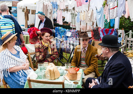 England, Chatham Dockyard. Veranstaltung, Gruß zu den 40er Jahren. Zwei Paare, trug 1940 Bekleidung, Outdoor Picknick sitzen um den Tisch zu plaudern. Stockfoto