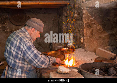 Ältere Mann in seiner Werkstatt Platten das Kupfer mit Zinn Schüssel in Mardin, Türkei. Stockfoto