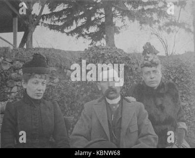 Amerikanisches Archiv Cyanotypisches Porträt eines Mannes mit Schnurrbart und zwei Frauen, die draußen mit Hüten und Mänteln sitzen. Aufgenommen im späten 19. Jahrhundert in Port Byron, NY, USA Stockfoto