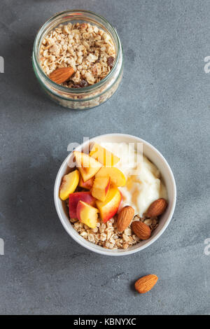 Hausgemachte Haferflocken Müsli mit Joghurt und Pfirsiche in Schüssel für gesundes Frühstück Müsli und Obst frühstück Schüssel mit Joghurt. Stockfoto