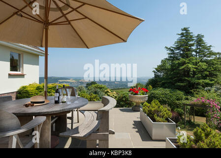 Flasche Wein und Gläser sitzen auf einem hölzernen Tisch vor einer atemberaubenden Blick über Dartmoor in der Grafschaft Devon, an einem sonnigen Sommer Stockfoto