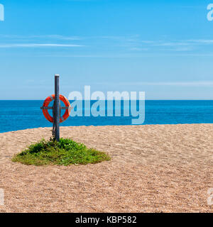 Einsame Strand bei slapton Sands, torcross, Devon, Großbritannien mit Leben Ring auf hölzernen Pfosten, blaues Meer und klare blaue Himmel. Meeresfrüchte Küste Stockfoto