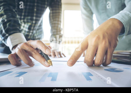 Business Team zwei Kolleginnen und Kollegen diskutieren, arbeiten mit vielen Dokument graph im Team Meeting sprechen Brainstorming Kommunikationskonzept. Stockfoto