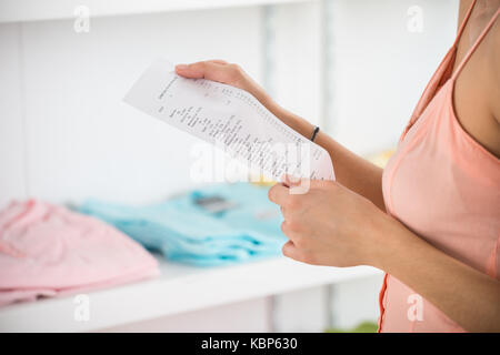 Mittelteil der jungen Frau mit Eingang im Bekleidungsgeschäft Stockfoto