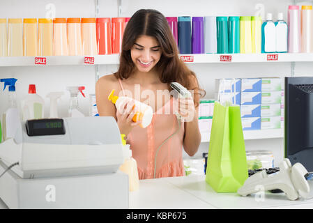 Junge Verkäuferin an der Kasse scannen Produkt im Laden Stockfoto