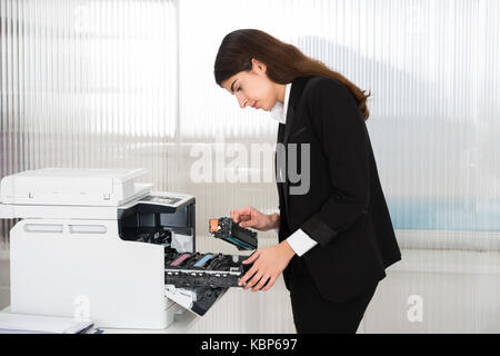 Seitenansicht der junge Unternehmer zur Festsetzung der Patrone im Drucker Maschine im Büro Stockfoto