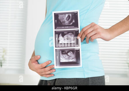Seitenansicht der Mittelteil der schwangeren Frau mit Ultraschall zu Hause scannen Stockfoto