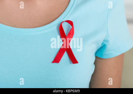 Mittelteil der Frau mit AIDS Awareness ribbon zu Hause Stockfoto