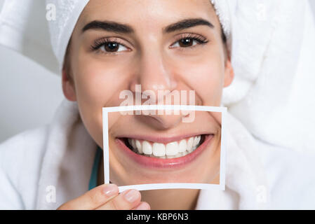 Schöne junge Frau mit Foto von toothy Lächeln zu Hause Stockfoto