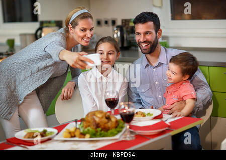 Freundliche Familie mit Kindern, die Weihnachten selfie am Tisch Stockfoto