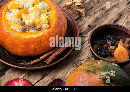 Kürbis Reisbrei in einen Kürbis auf einem Herbst Hintergrund zubereitet Stockfoto