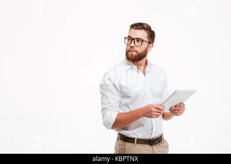 Bild von schweren Jungen bärtigen Mann stand in der Nähe von Copyspace über weiße Wand Hintergrund isoliert. Neben der Suche mit Tablet-PC. Stockfoto
