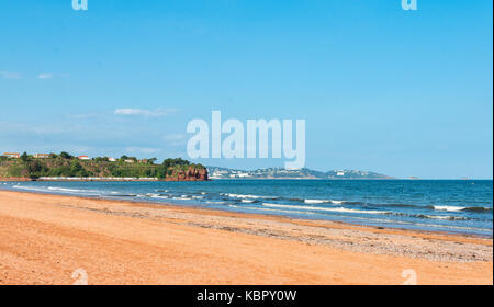 Einsame Sandstrand bei Goodrington Sands, Paignton, Devon, Großbritannien mit Torquay in der Ferne an einem klaren blauen sonnigen Sommer. Stockfoto