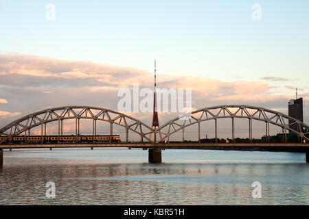 Riga Radio- und TV-Turm mit eisenbahnbrücke am Sonnenuntergang Stockfoto