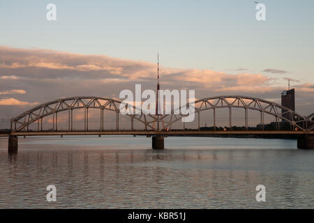 Riga Radio- und TV-Turm mit eisenbahnbrücke am Sonnenuntergang Stockfoto