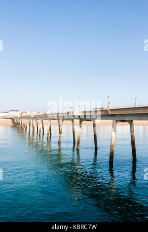 England, Pier. Blick auf die Länge der Pier und der Strand mit einem Teil der Stadt. Strahlend blauer Himmel, tagsüber, strahlendem Sonnenschein. Sehr ruhiges Meer. Stockfoto