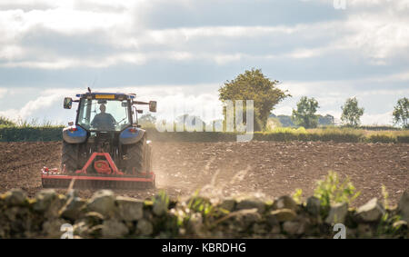 Landarbeiter, die das Feld für das Pflügen von Traktoren in East Lothian, Schottland, Großbritannien antreiben Stockfoto