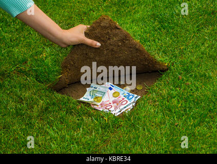 Finanzen Konzept, Hände Geld versteckt sich unter dem Gras Stockfoto