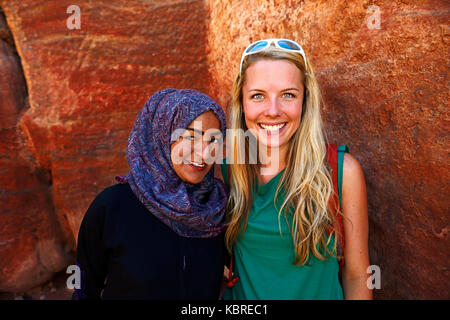 Touristische Mädchen wirft mit lokalen Beduinen Mädchen an farbenfrohen Felsformationen in Petra, Wadi Musa, Jordanien Stockfoto