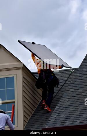 Solar Panel Techniker mit Solarmodulen bis Leiter auf das Dach eines Hauses Stockfoto