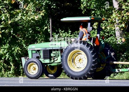 Farmer John Deere Traktor fahren die Straße runter Stockfoto