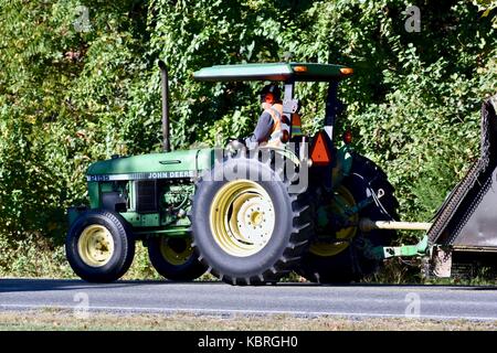 Farmer John Deere Traktor fahren die Straße runter Stockfoto