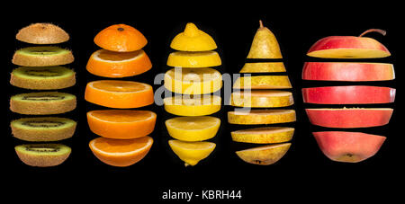 Kreatives Konzept mit Lebensmitteln. Satz von geschnittenem Obst auf schwarzem Hintergrund isoliert. Fliegen, Zitrone, Orange, Kiwi, Birne, Apfel. Leichtsinn Obst schwebend, in der ein Stockfoto
