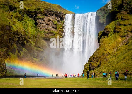 Island, Skogafoss Wasserfall mit doppelter Regenbogen und Touristen bewundern die Wunder das Natur Stockfoto