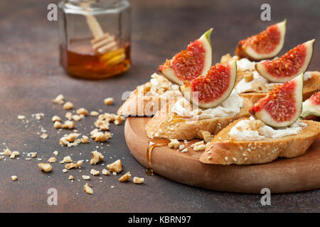 Sandwiches mit Feigen, Ricotta, Honig und Walnüssen auf braunem Hintergrund Stockfoto