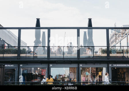 Menschen vorbei gehen und sitzen am Dach Cafe an BOXPARK Shoreditch, Versandverpackung, Pop-up-Mall für unabhängige und Modegeschäfte. Stockfoto