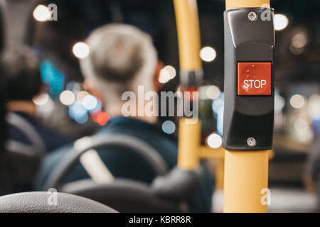 Schließen Sie die rote Stopptaste inside Double Decker Bus in London, die Passagiere auf den Hintergrund. Stockfoto