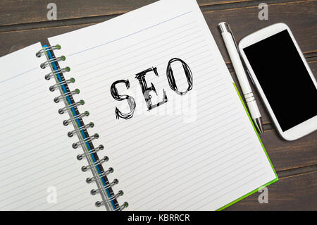 Seo (Search Engine Optimization) in einem Notebook mit einem Smart Phone auf Tisch, Geschäftskonzept. Stockfoto