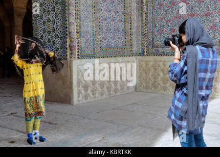 Provinz Fars, Shiraz, Iran - 19. April 2017: Das Mädchen Fotograf Fotos ein Modell in einem Nationalen Iranischen Anzug, in der Nähe der Eingang zur Moschee. Stockfoto