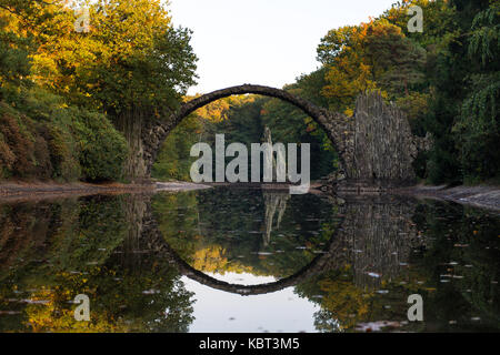 Bad Muskau, Deutschland. 29 Sep, 2017. Die Rakotz Brücke und Bäume im Herbst Farben werden in einem See in einem Park in Bad Muskau, Deutschland, 29. September 2017 wider. Credit: Monika Skolimowska/dpa-Zentralbild/dpa/Alamy leben Nachrichten Stockfoto