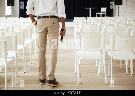 7/8 Image der jungen afrikanischen Mann, der im Büro drinnen halten Mikrofon. Stockfoto