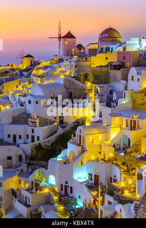 Luftaufnahme der Stadt Oia, Santorini, Griechenland bei Sonnenuntergang. Traditionelle und berühmte weisse Häuser und Kirchen mit blauen Kuppeln auf die Caldera, aege Stockfoto