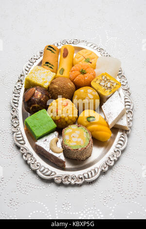 Foto der Indischen Spezialitäten serviert in Silber oder Holzplatte. Vielzahl von Peda, burfi, laddu in dekorative Platte, selektiver Fokus Stockfoto