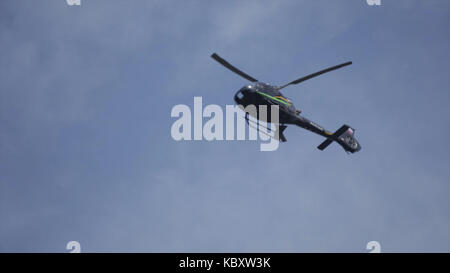 Hubschrauber in den bewölkten Himmel mit Blitz. Hubschrauber von unten Fliegen durch den bewölkten Himmel. Schwebenden Hubschrauber gegen Helle, sonnige und bewölkter Himmel Stockfoto