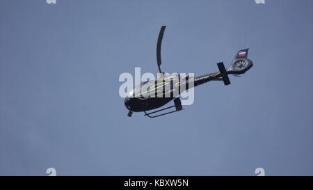 Hubschrauber in den bewölkten Himmel mit Blitz. Hubschrauber von unten Fliegen durch den bewölkten Himmel. Schwebenden Hubschrauber gegen Helle, sonnige und bewölkter Himmel Stockfoto