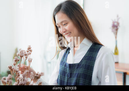 Asiatische Frau Blumenhändler auf Dekorieren mit Blumen in Vase in Shop mit lächelnden Gesicht konzentriert. Stockfoto