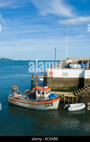 Bunte Fischerboot am Eingang zum Hafen von Paignton, Devon, Großbritannien mit Torquay in der Ferne an einem sonnigen Sommer vertäut. Meeresfrüchte Küste Stockfoto