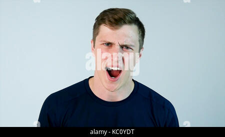 Ein junger Mann schreit die kamera mit schwarzem T-Shirt und grauer Hintergrund Stockfoto