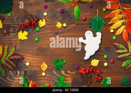 Schönen festlichen Hintergrund für Halloween mit Lebkuchen, Herbst Blätter, Beeren und Süßigkeiten auf einem Holztisch. freier Speicherplatz Stockfoto