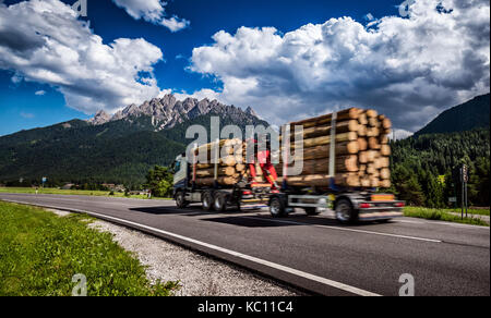 Holz Lkw Rast auf der Autobahn im Hintergrund die Alpen. Lkw Auto in Bewegungsunschärfe. Stockfoto