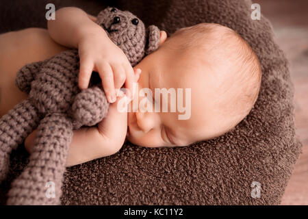 Neugeborene schlafen in einem schönen Stellen mit einem kleinen Bären Stockfoto