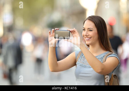 Single Frau die Bilder mit einem Smart Phone auf der Straße Stockfoto